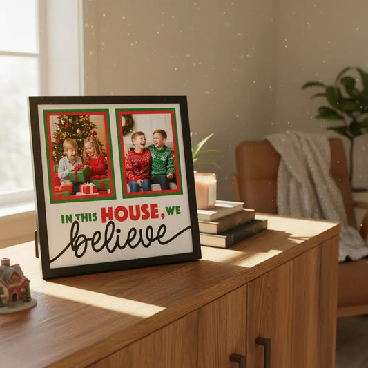 Decorative sign with text 'In this house, we believe' and two blank photo frames.