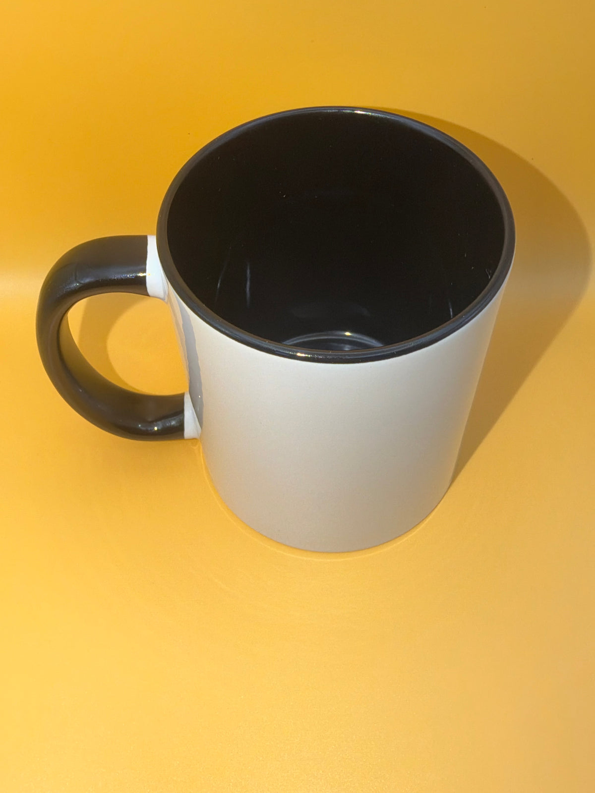 Black mug showing its coloured interior and handle
