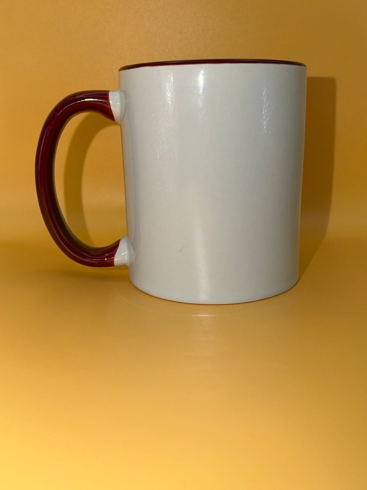 White mug with a maroon handle, shown from the side