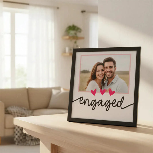 Decorative sign with 'engaged' text and three pink hearts on a light pink background.