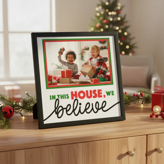 Decorative sign with text 'In this house, we believe' in a festive color scheme.