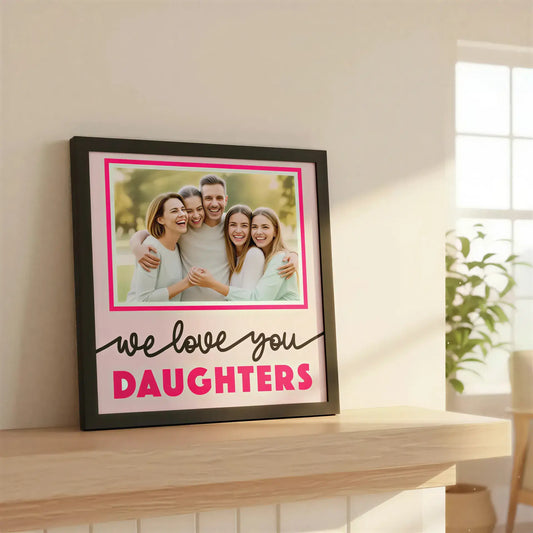 Decorative photo frame with 'we love you DAUGHTERS' text on a pink background
