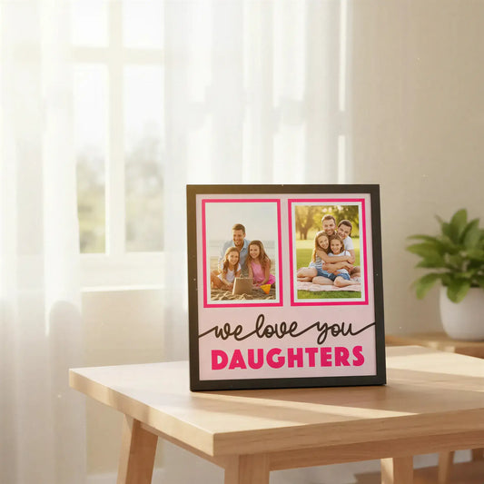 Decorative wall art with two photo frames and text 'we love you DAUGHTERS' on a pink background.