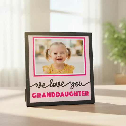 Decorative photo frame with 'we love you granddaughter' text and pink border.